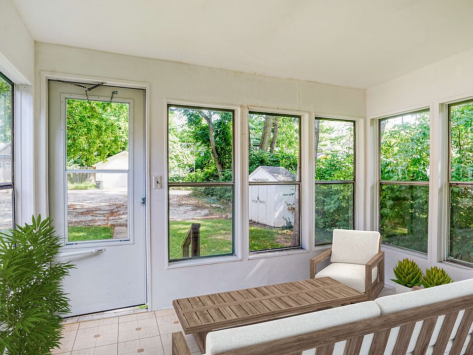 right sunroom with multiple windows covered by blinds and a door leading outside, featuring white walls and tiled floor.
