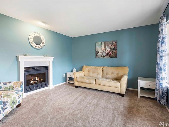 The formal living room features new carpeting, gas fireplace with tile surround and white mantle, display light and a large window that lets in plenty of natural light.