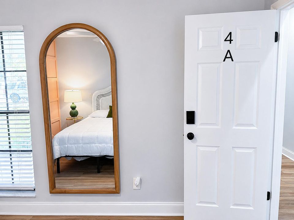 Private bedroom with wood-look flooring, ample wall space, and a window with blinds, furnished with a comfortable bed.