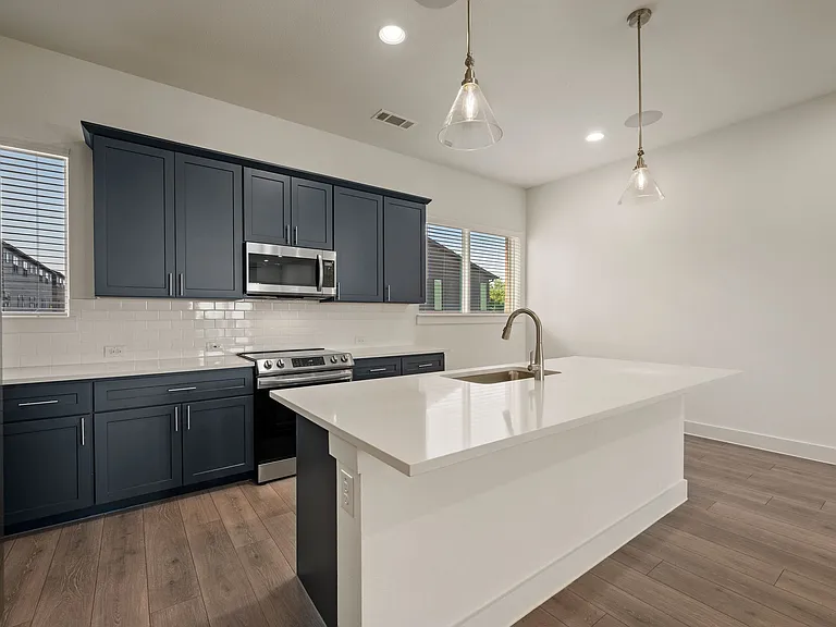 Kitchen view with beautiful island that seats four with elegant pendant lighting.