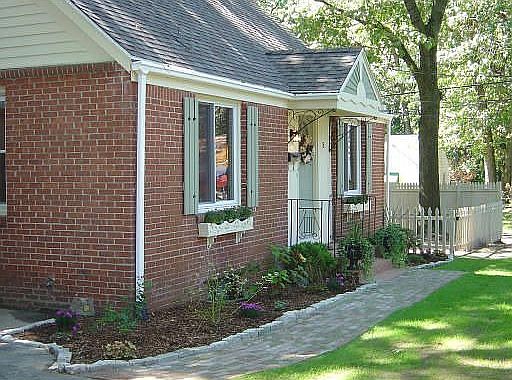 New lawn, flowering shrubs, perennials, brick walkway.