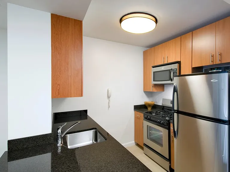 Classic I North kitchen with stainless steel appliances, black granite countertops, maple cabinetry, and cream tile flooring