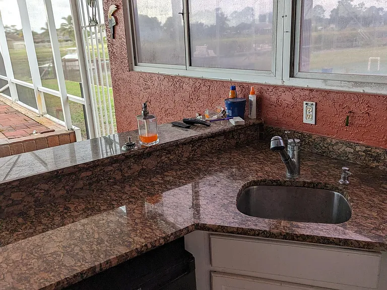 Outdoor kitchen with granite countertops, stainless steel sink, power outlets and a water-view.