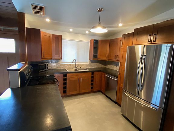 kitchen adjacent to living room, stainless steel refrigerator, dishwasher, stove, and microwave