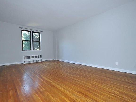 Large Corner Living Room with Hardwood floors opens to the dining foyer and overlooking Tree Lined Garth Road. The living room is 19'-10" x 12'-2".