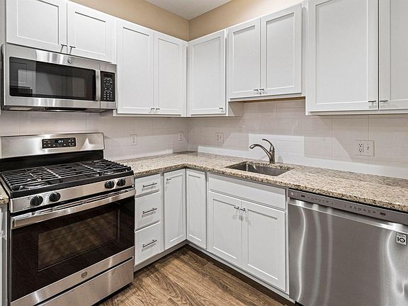 Kitchen with white cabinets, granite countertops & stainless steel appliances.
