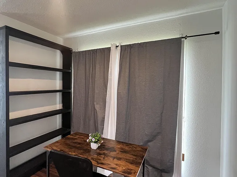 Dedicated work nook with a desk, chair, and built-in shelving, plus window coverings for privacy and light control.