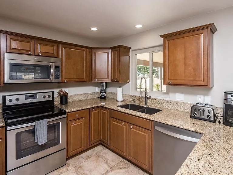 Bright kitchen workspace with dual-basin sink, large window for natural light, and modern finishes throughout.