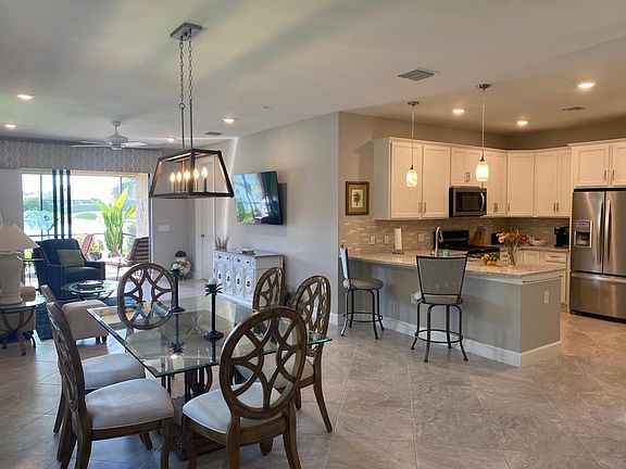 Bright open living space with stainless appliances, fully stocked kitchen, dining and living room open to lanai