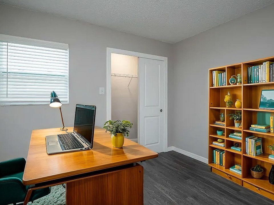 Modern home office with a sleek wooden desk, vibrant teal chair, and a stylish bookcase filled with books and decor.