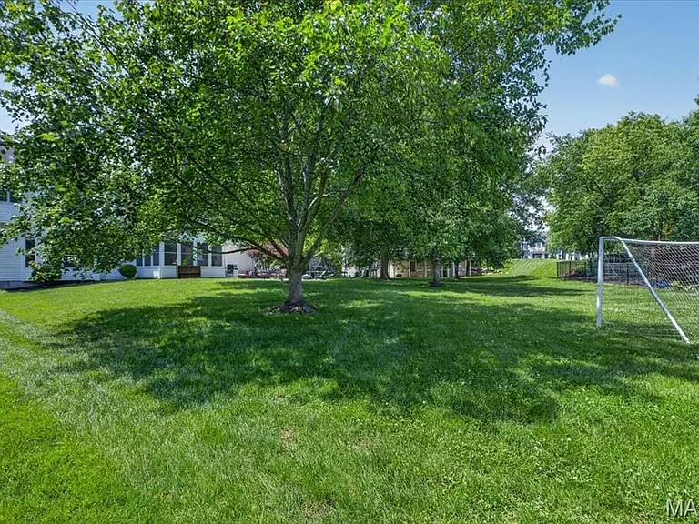 Expansive green lawn with mature trees providing natural shading