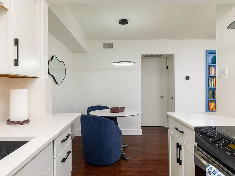 A cozy dining nook with plush navy chairs and a modern round table. Ideal for meals, planning your day, or relaxing with good company.