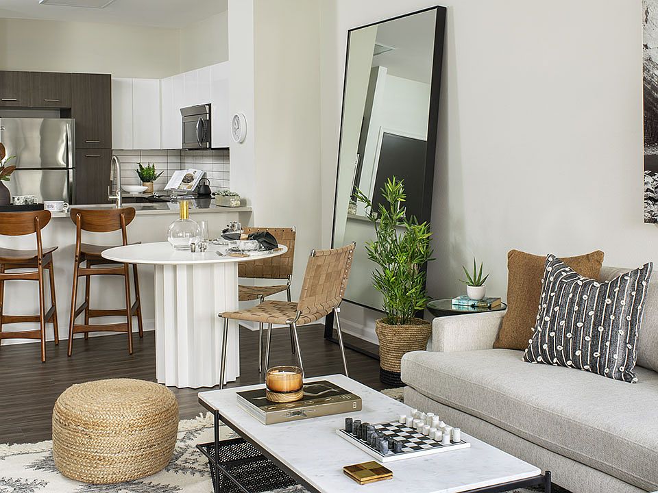 Apartment kitchen with stainless steel appliances, dining and living room with wood-style flooring.