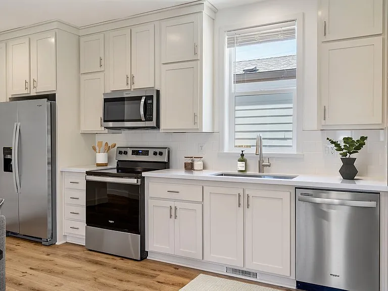 Freestanding Home kitchen with stainless steel appliances, white quartz countertops, white subway tile, white cabinetry, and hard surface flooring
