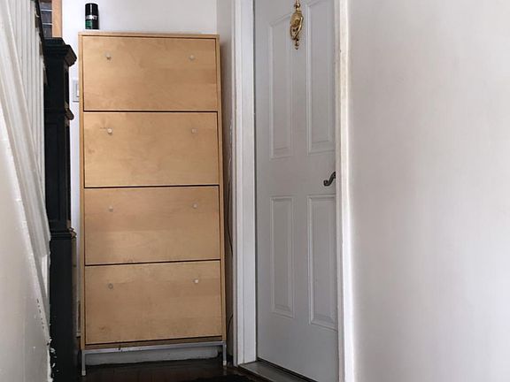 The entrance and door to the apartment, shoe storage provided by door.