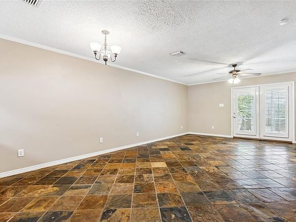 Spare room featuring a textured ceiling, crown molding, and dark tile patterned floors