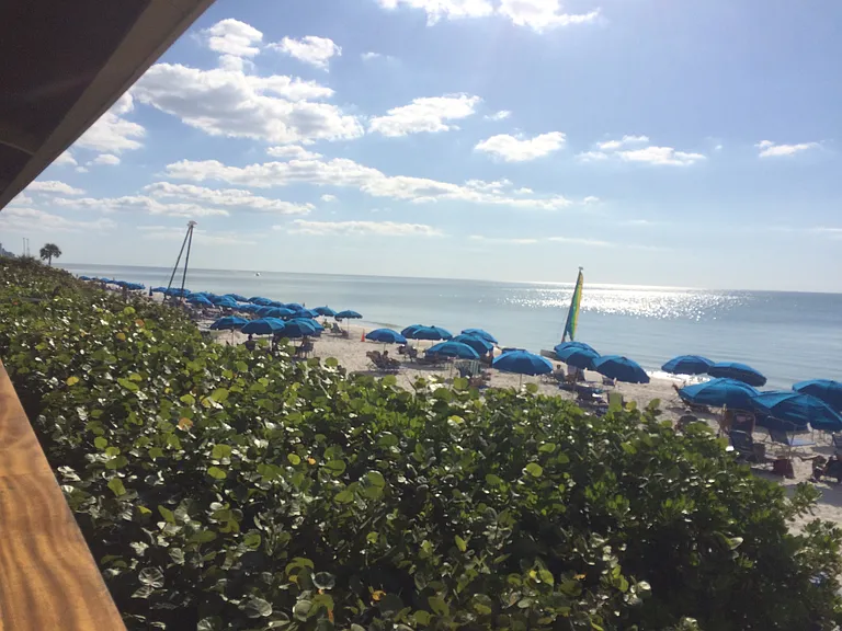 Private beach with free amenities including chairs, tables, umbrellas, cabanas, sailboats, kayaks, paddleboards, cornhole, showers, and restrooms