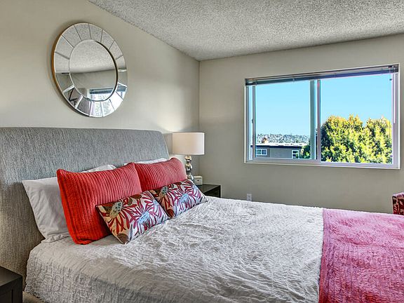 A bedroom with two nightstands and a bed with a large window overlooking the property