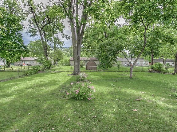 Fenced, large flate yard with mature trees.