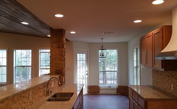 Granite Counters and accent back splash plus custom cabinets. You can also see the recessed lighting and beaded ceiling in the living area. The kitchen vent is vented to the roof.