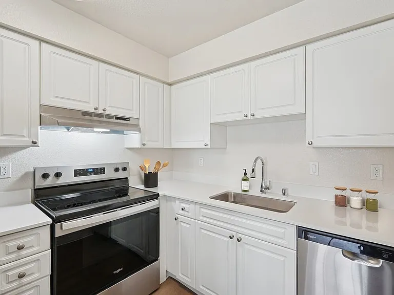 Renovated Package I kitchen with stainless steel appliances, white cabinetry, quartz countertops, and hard surface flooring