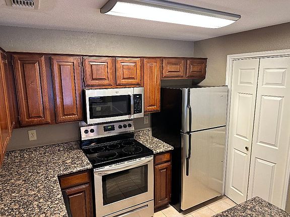 Kitchen with granite countertops, stainless steel appliances, and laundry closet with full-size washer & dryer