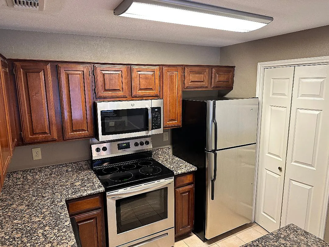 Kitchen with granite countertops, stainless steel appliances, and laundry closet with full-size washer & dryer - 12660 Hillcrest Rd #1201
