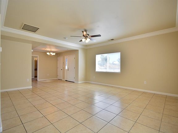 Large living room with beautiful crown molding, new ceiling fan and tile flooring