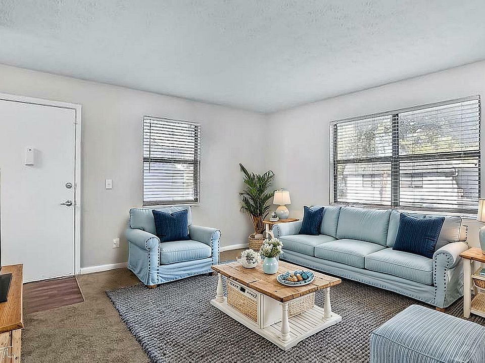 Charming living room with cozy blue sofas and elegant decor, flooded with natural light from large windows, creating a serene and inviting atmosphere.