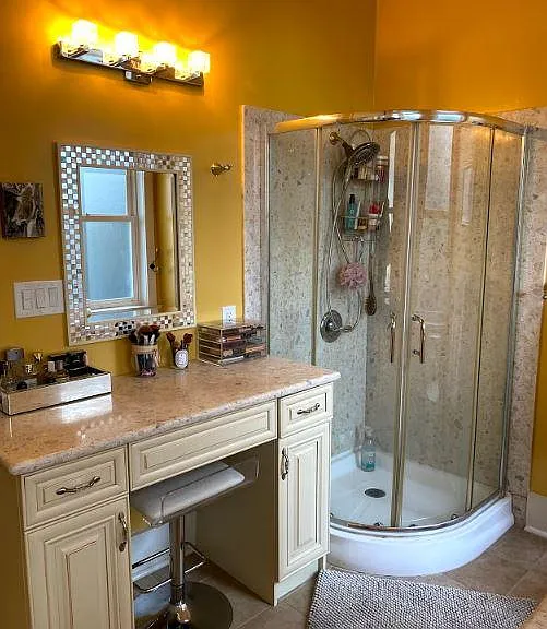 View of makeup vanity and shower stall. Mirror and marble match.