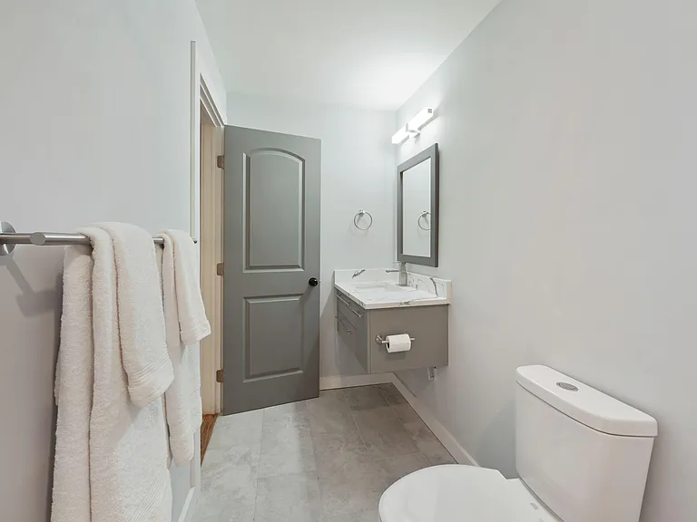 Clean bathroom with a floating vanity, stone-look counter, framed mirror, and tile flooring for easy upkeep.