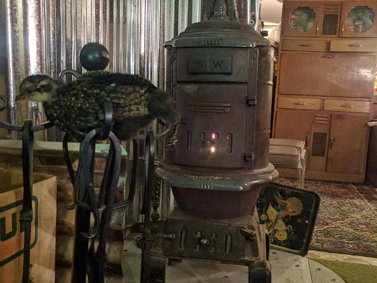 Newly installed wood stove in main area of the house dining room/kitchen and the narrow hallway to the left that houses the laundry facilities