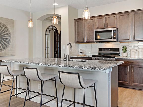 The large kitchen island features beautiful granite and accent light fixtures perfect for enjoying y