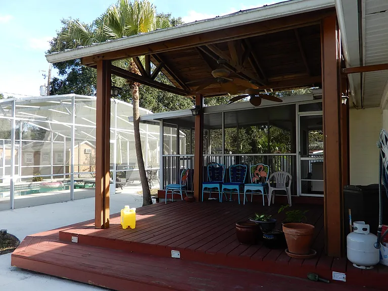 Large gazebo attached to rear of house with 2 ceiling fans.