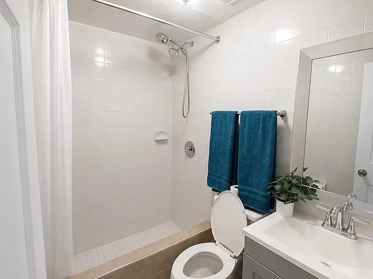 Full bathroom with tiled tub/shower combo, updated vanity with storage, and a large wall mirror for easy daily routines.