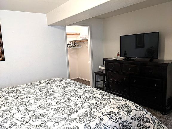 The other side of the room is a dresser and a smart TV on top of it. A large walk-in closet is at the corner.