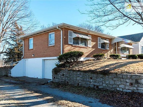 North side view with retaining wall, driveway, garage and "people" doors
