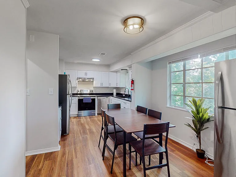 Eat-in kitchen with white cabinetry, stainless-steel appliances, ample counters, and a dining nook beside a large window.