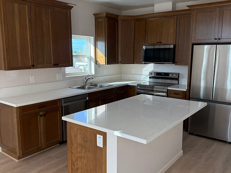 Kitchen with large island and new stainless appliances: refrigerator, stove/cooktop, microwave, dishwasher and garbage disposal
