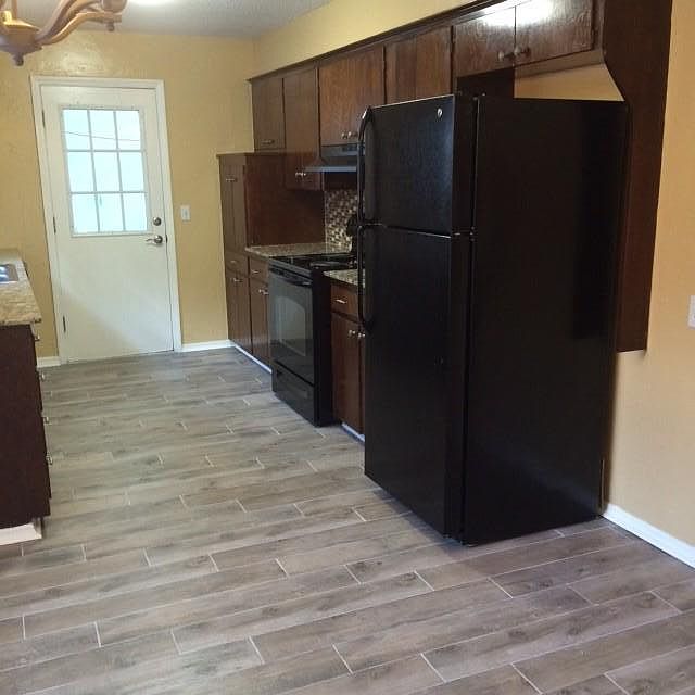 Kitchen with plank ceramic tile and glass backsplash