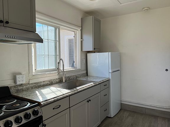 Range/oven, refrigerator, stainless steel sink and pull-out faucet in kitchen