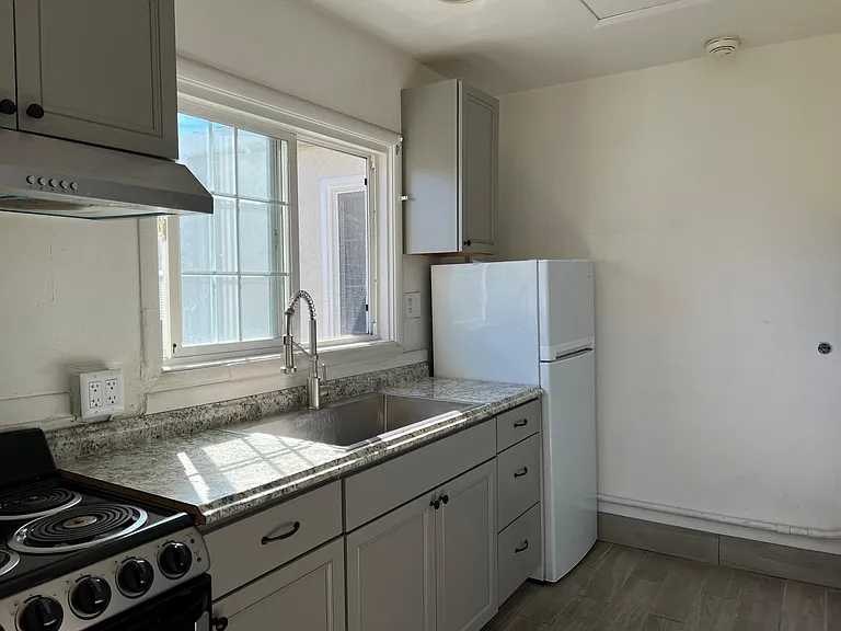 Range/oven, refrigerator, stainless steel sink and pull-out faucet in kitchen