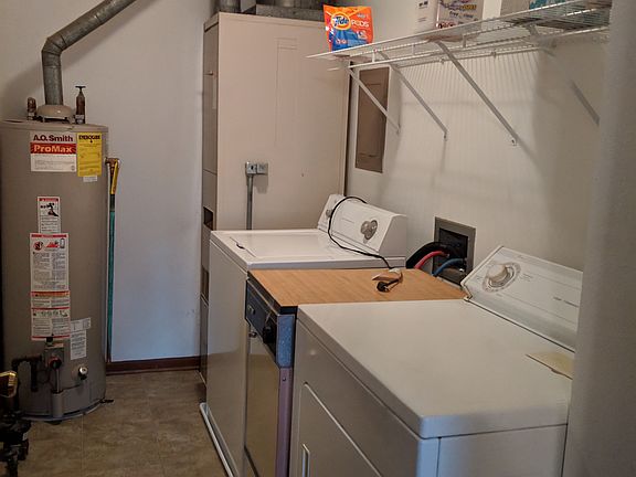 Utility room. Orphaned portable dishwasher between washer & dryer. Crawl space access here.