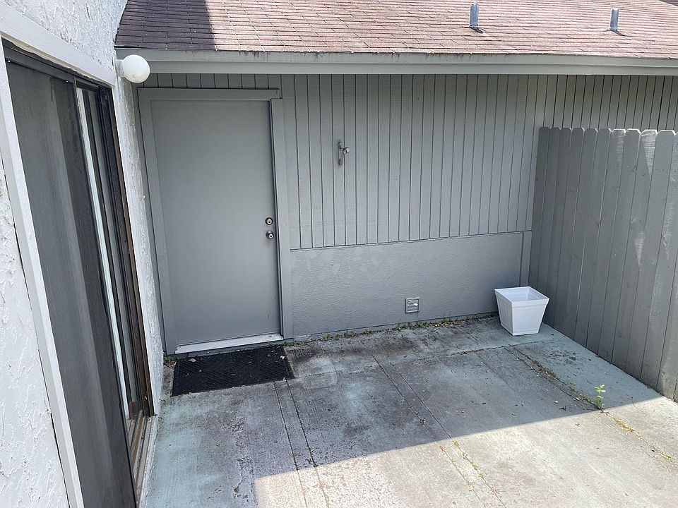 Photo of fenced patio with sliding glass patio doors off of the living room and back door leading into garage