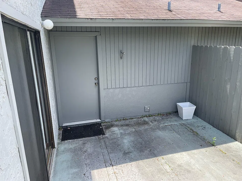 Photo of fenced patio with sliding glass patio doors off of the living room and back door leading into garage
