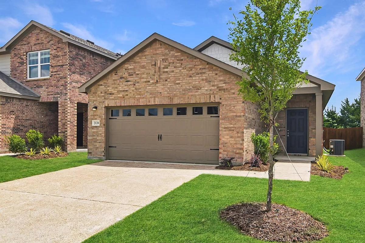 Brick exterior featuring a two-car garage with windows, a covered entryway, and a concrete driveway - 2120 Prairie Ln