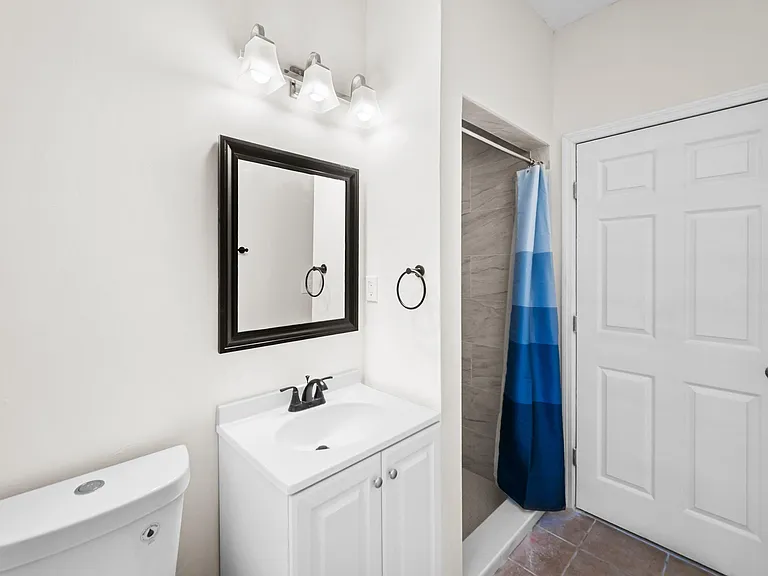 Clean bathroom with a single-sink vanity, framed mirror, and a tiled shower/tub combo with curtain.