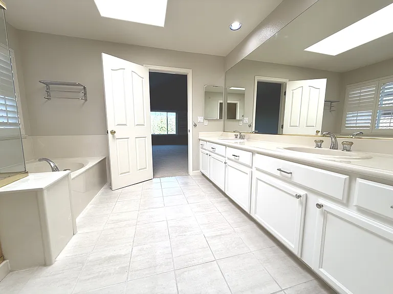 Primary Bathroom with dual sink vanity and skylight