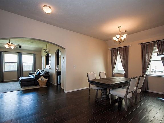 View of dining room and living room. Arched door ways. Natural lighting and lights inside of the house. Porcelain wood tile floor. Very open. Long curtains add to the view.