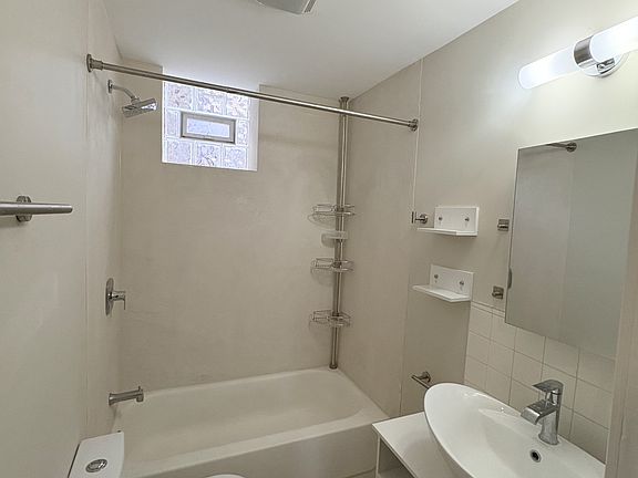 Modern bathroom with full tub/shower, contemporary vanity, and clean, neutral finishes